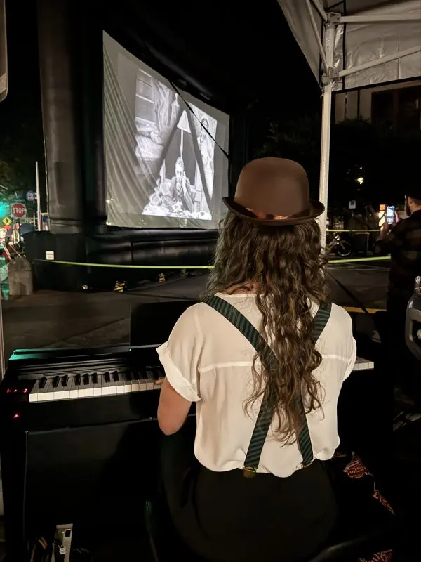 Person playing piano with film screen the the background