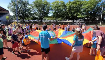 Kids and event staff play with a large parachute