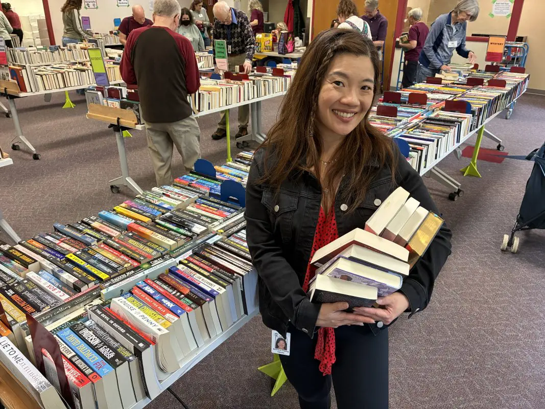 A woman holding a stack of books