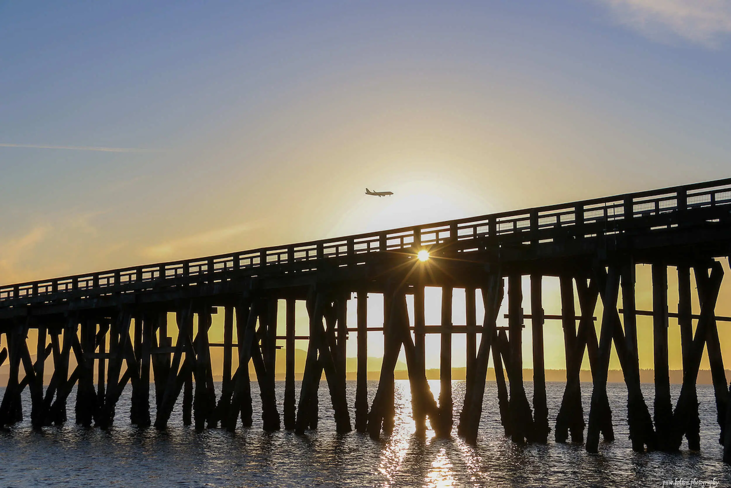 The sun sets behind a pier.