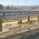 A rendering of a large skatepark under an overpass bridge