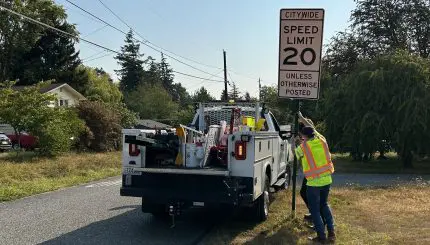 Construction workers install a roadside sign