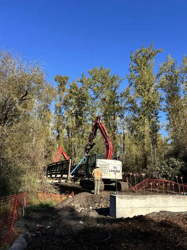 Large construction equipment in front of a pedestrian bridge