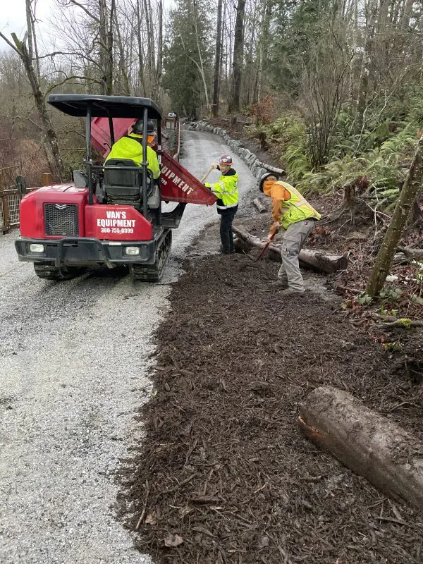 Workers add bark next to trail