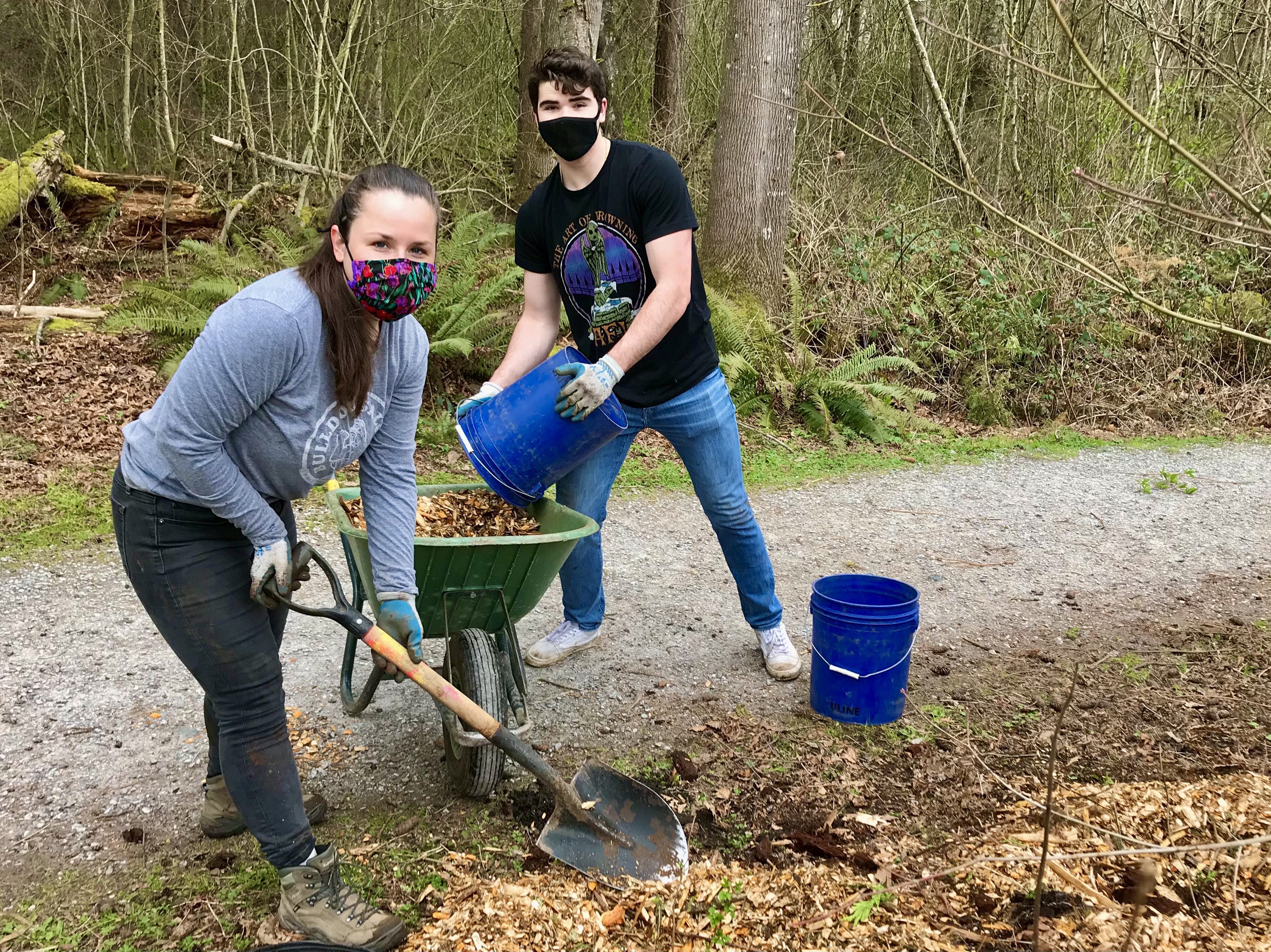 two adults volunteering by a natural trail