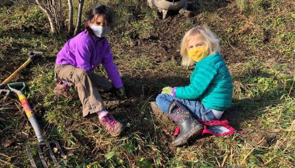 two kids in natural space helping plant a tree