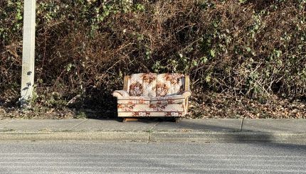 Old floral couch sitting on a sidewalk