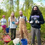Four adults smile in the woods at a work party