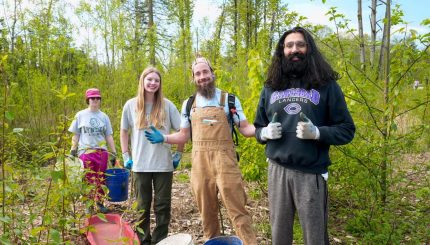 Four adults smile in the woods at a work party