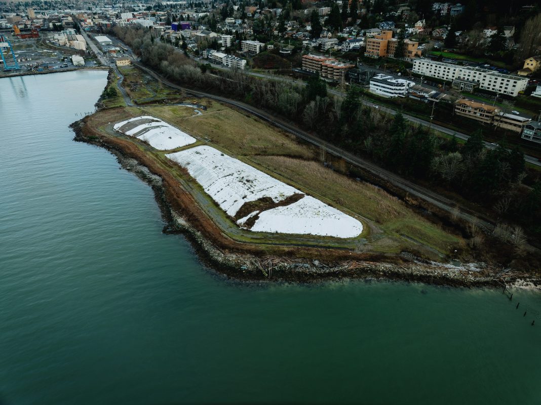 Aerial view of waterfront construction site with large white tarps