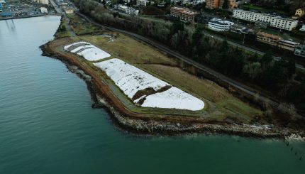 Aerial view of waterfront construction site with large white tarps