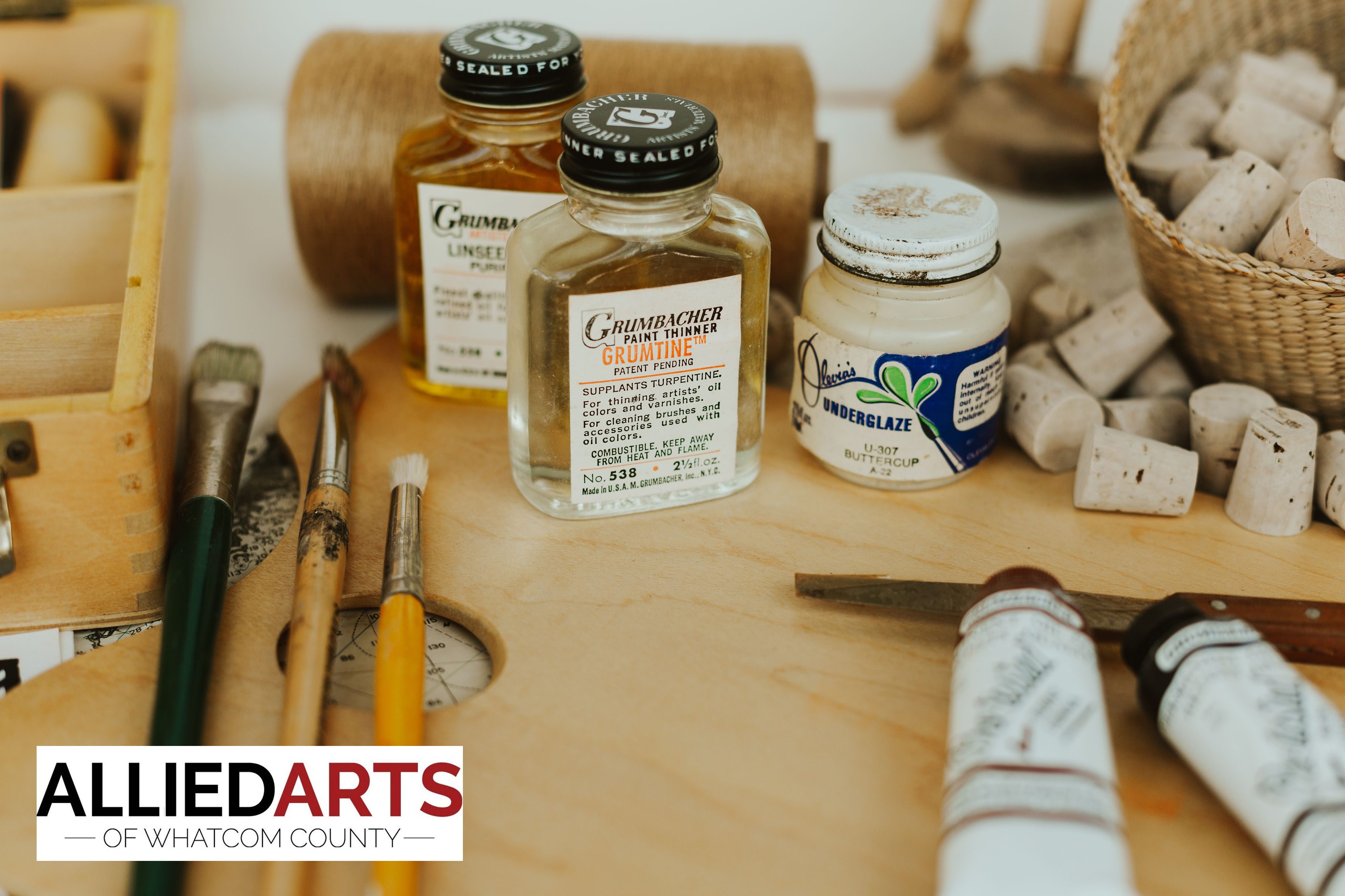 Various art supplies such as paintbrushes, an easel, paint thinner, and corks sitting on a table.