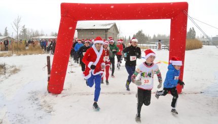 Participants running under a red arch at the start of the Santa 5K.