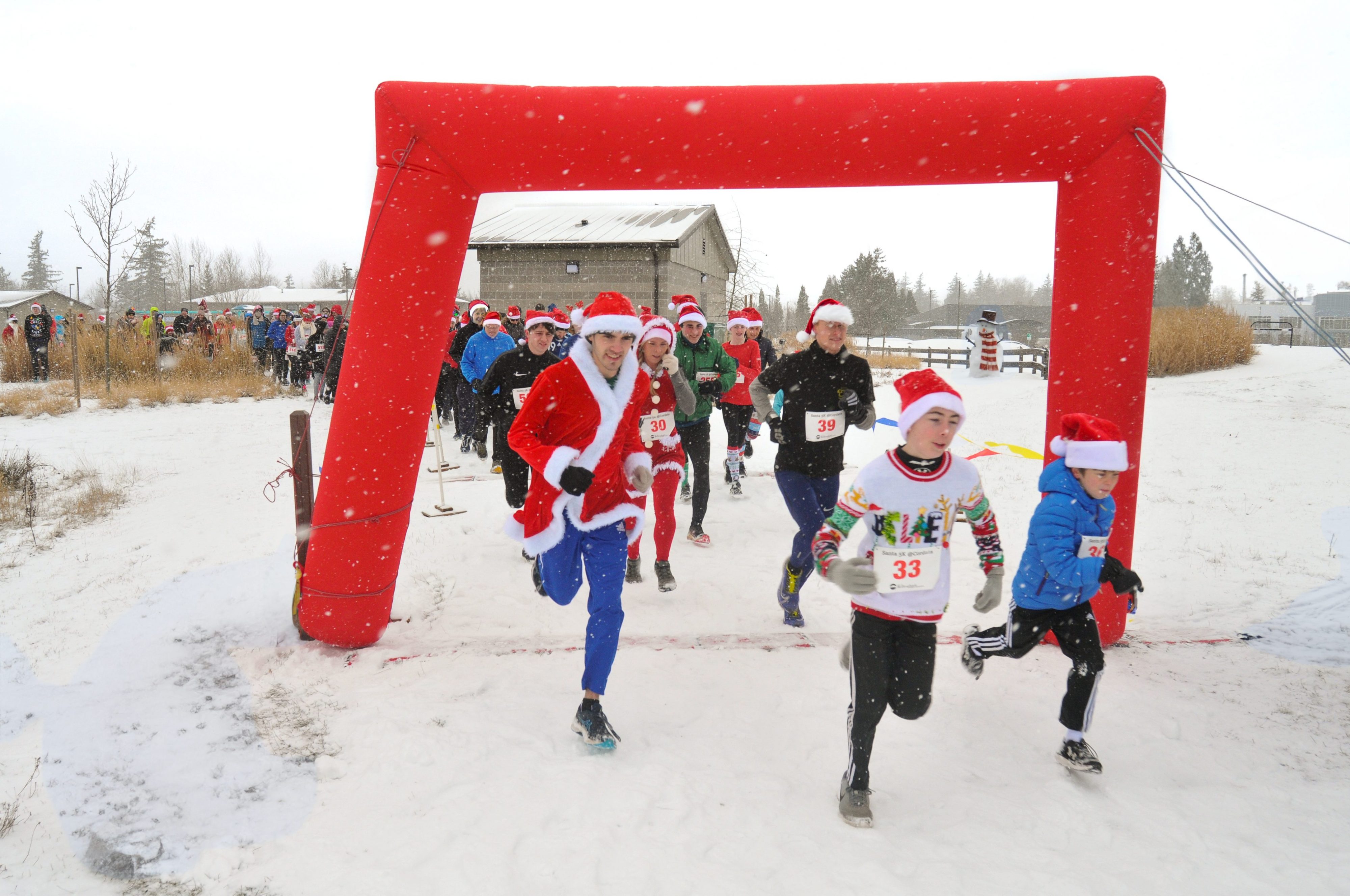 Participants running under a red arch at the start of the Santa 5K.