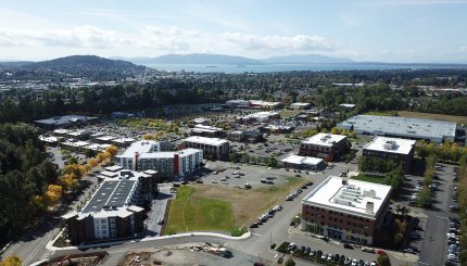 Aerial of Barkley Village shows large buildings in the foreground and the bay and islands in the background.