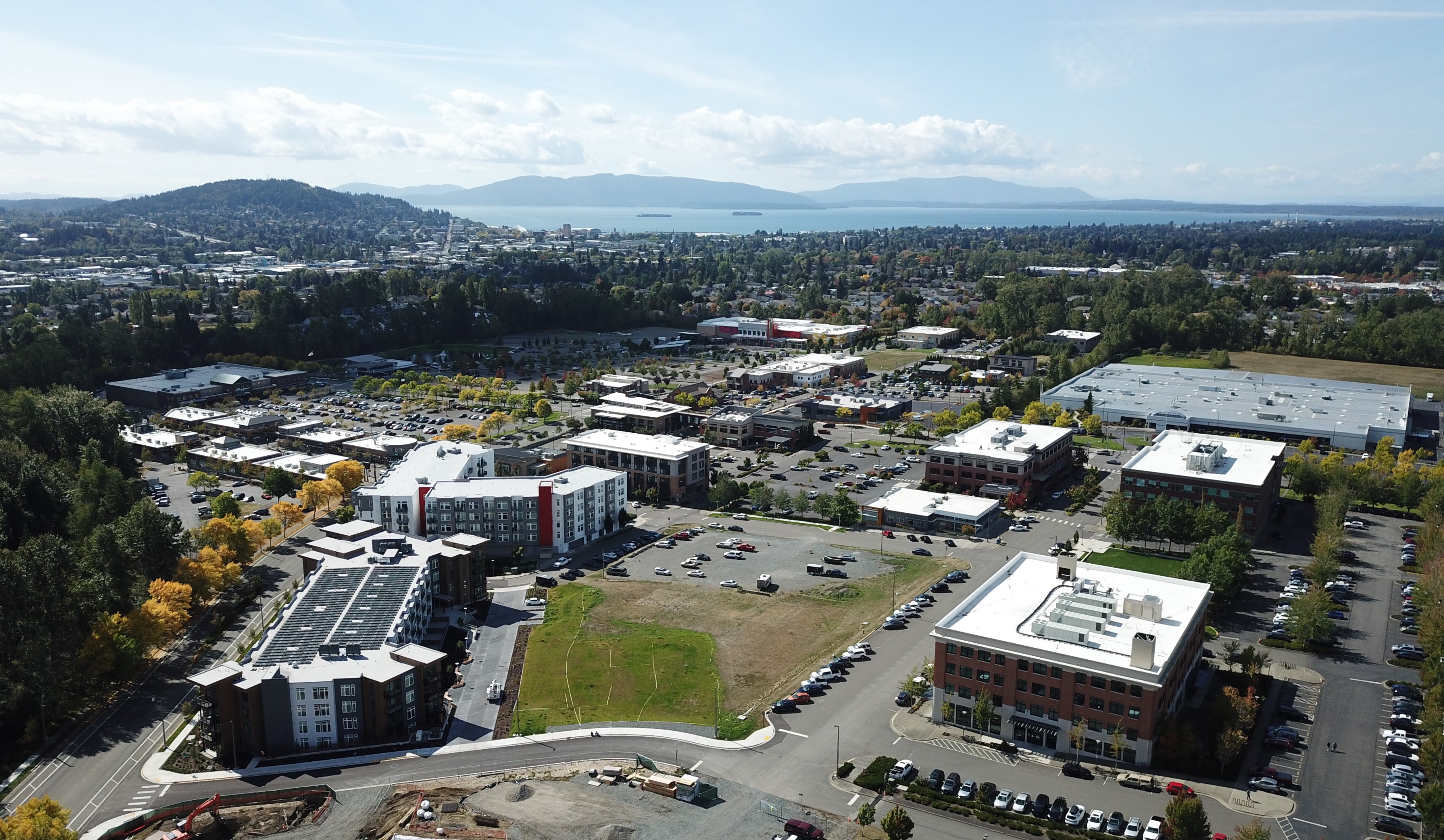 Aerial of Barkley Village shows large buildings in the foreground and the bay and islands in the background.