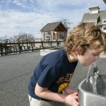 Boy drinking from water fountain outside