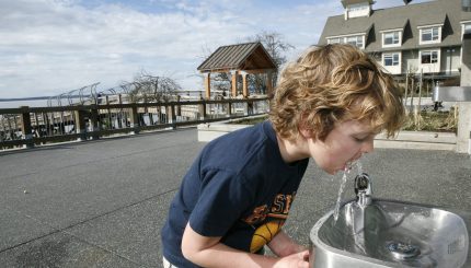 Boy drinking from water fountain outside