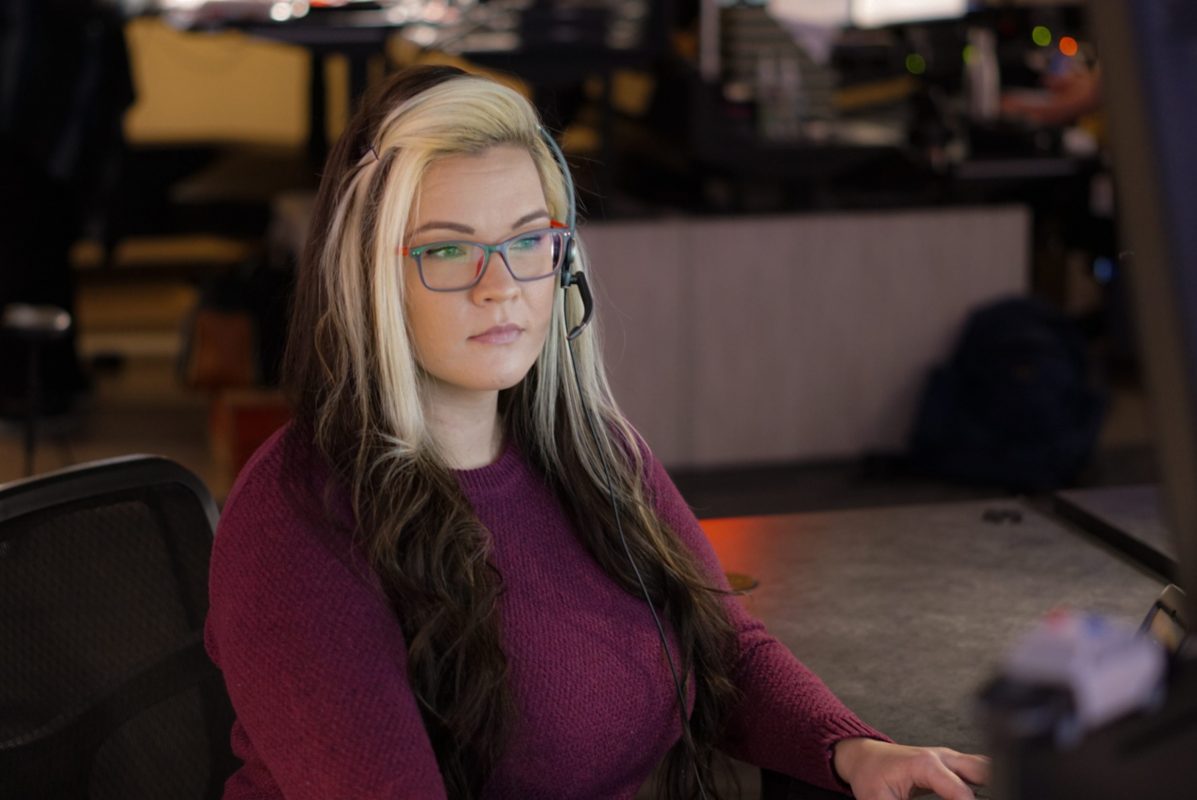 911 dispatcher with headset sitting at desk