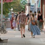 Two people hold hands while walking on a downtown Bellingham sidewalk.