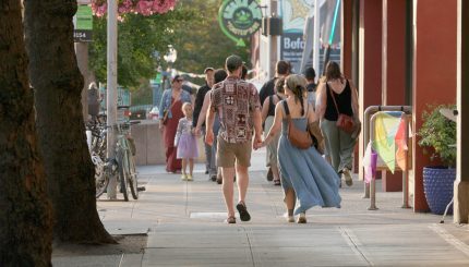 Two people hold hands while walking on a downtown Bellingham sidewalk.