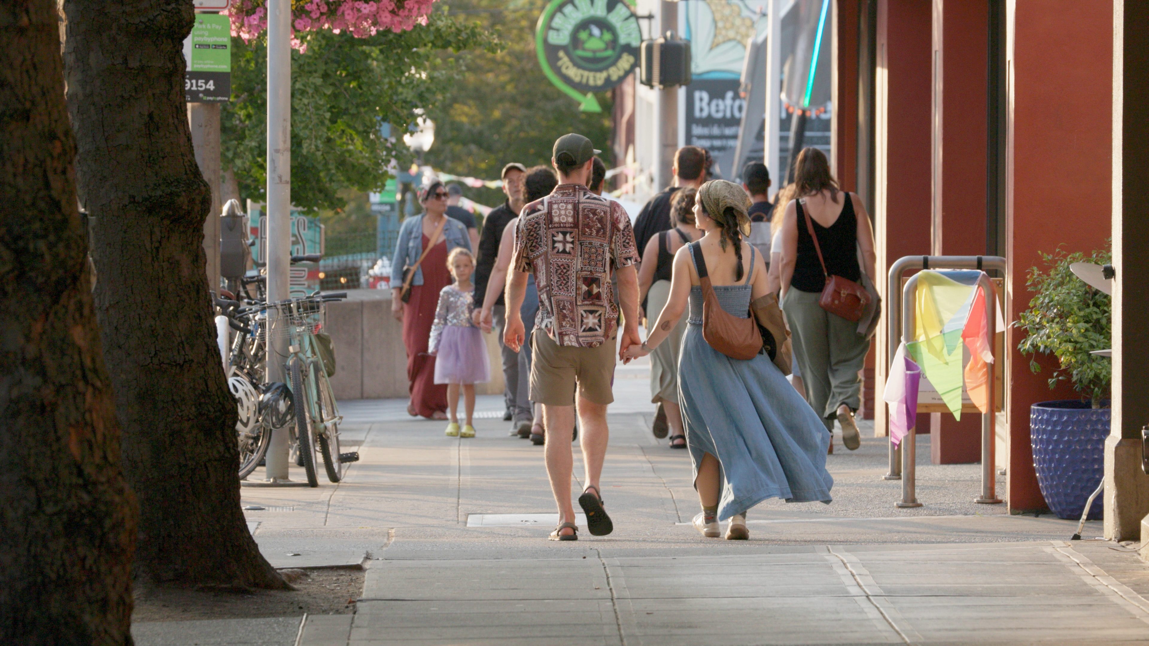 Two people hold hands while walking on a downtown Bellingham sidewalk.