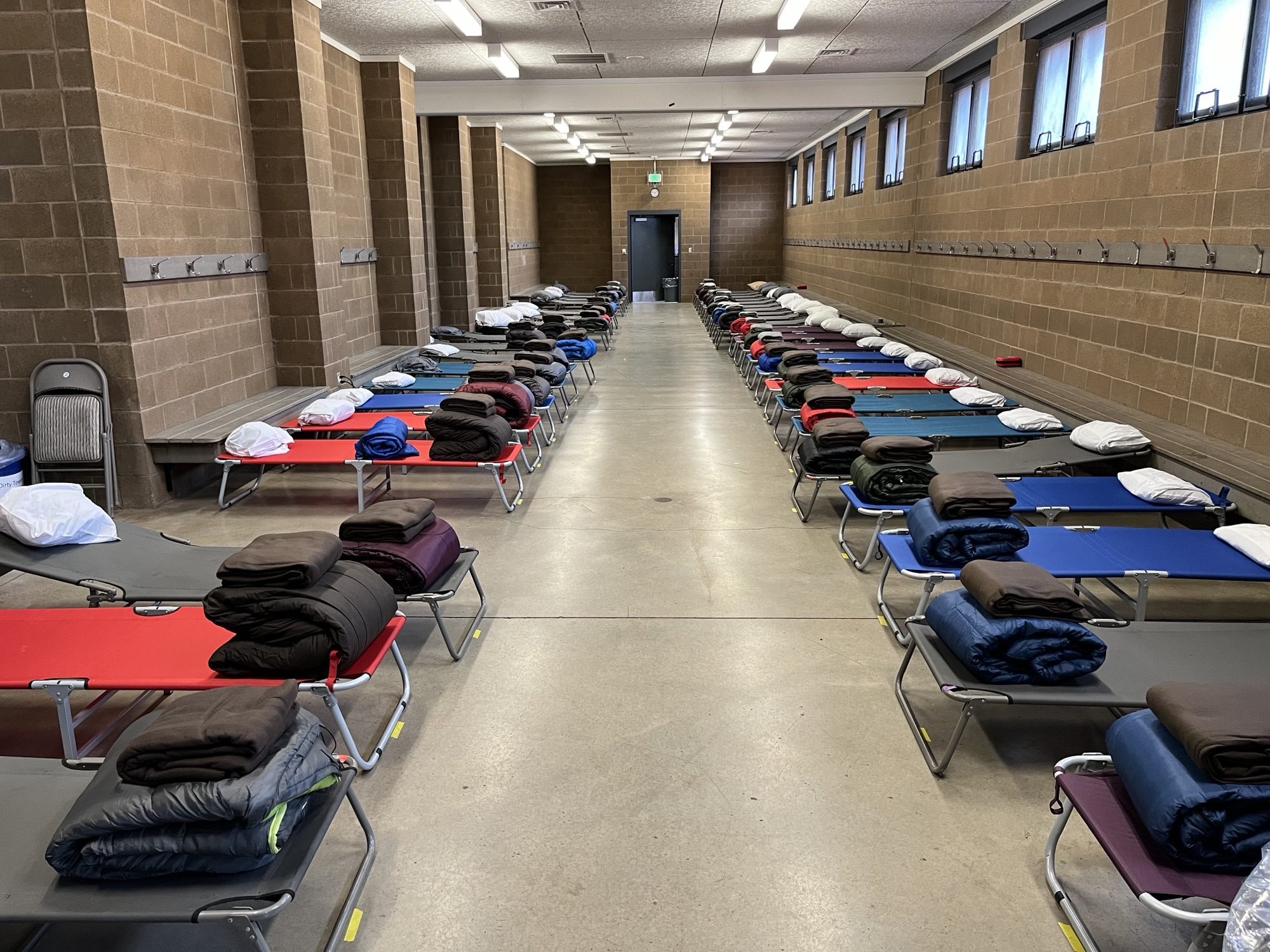 Two rows of cots with an aisle in the middle in a Civic Field locker room.