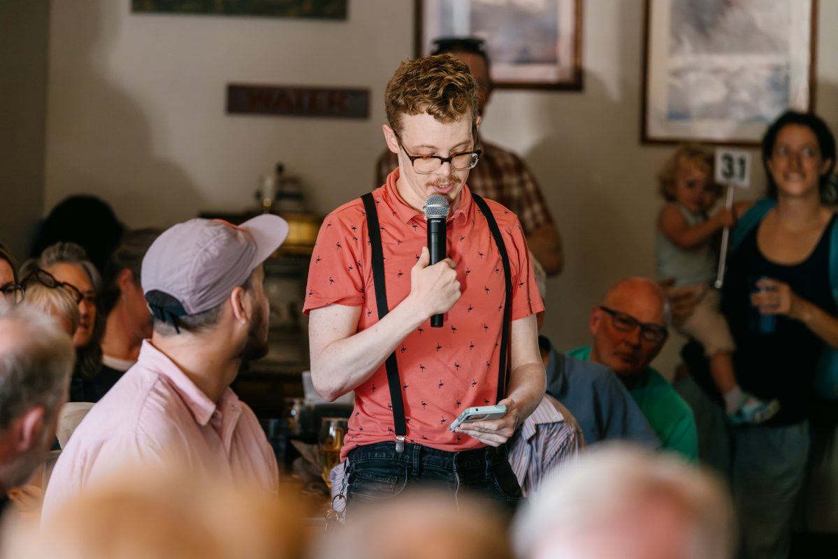 A person stands in a crowd speaking from a mic