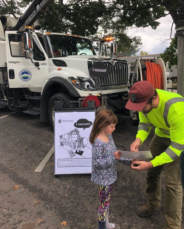 Small child talking with a Public Works employee in front of a parked big truck