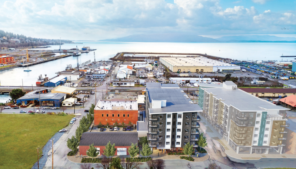 An aerial artist rendering shows an apartment building in an old, waterfront neighborhood