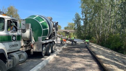 Construction workers guiding cement from cement truck into area for new sidewalk