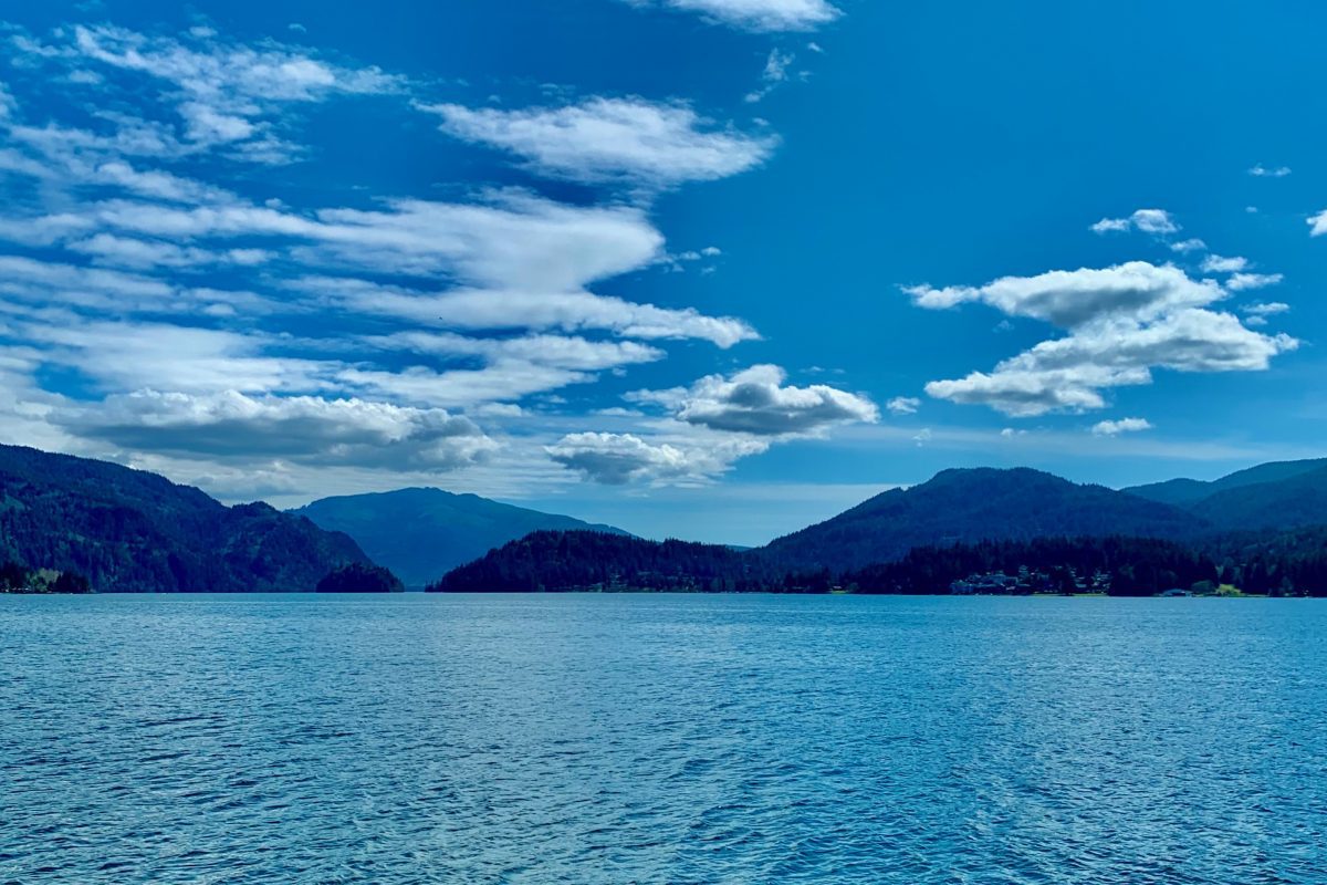 Lake with hills in the background and a bright blue sky