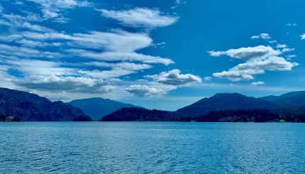 Lake with hills in the background and a bright blue sky