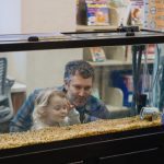 adult and young child look into fish tank with gravel on the bottom