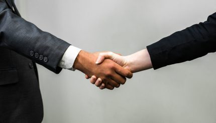 Young Hispanic businessman shake hands with young white businesswoman