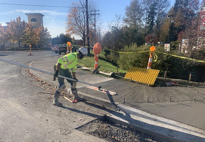 Worker using tool to flatten wet cement for new sidewalk