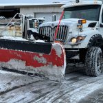 snow covered plow parked in parking lot