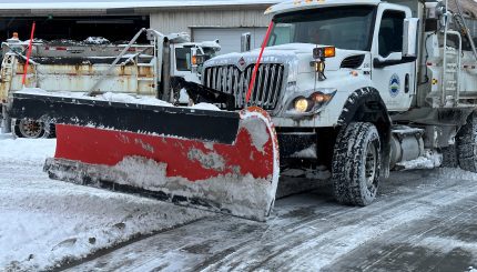 snow covered plow parked in parking lot