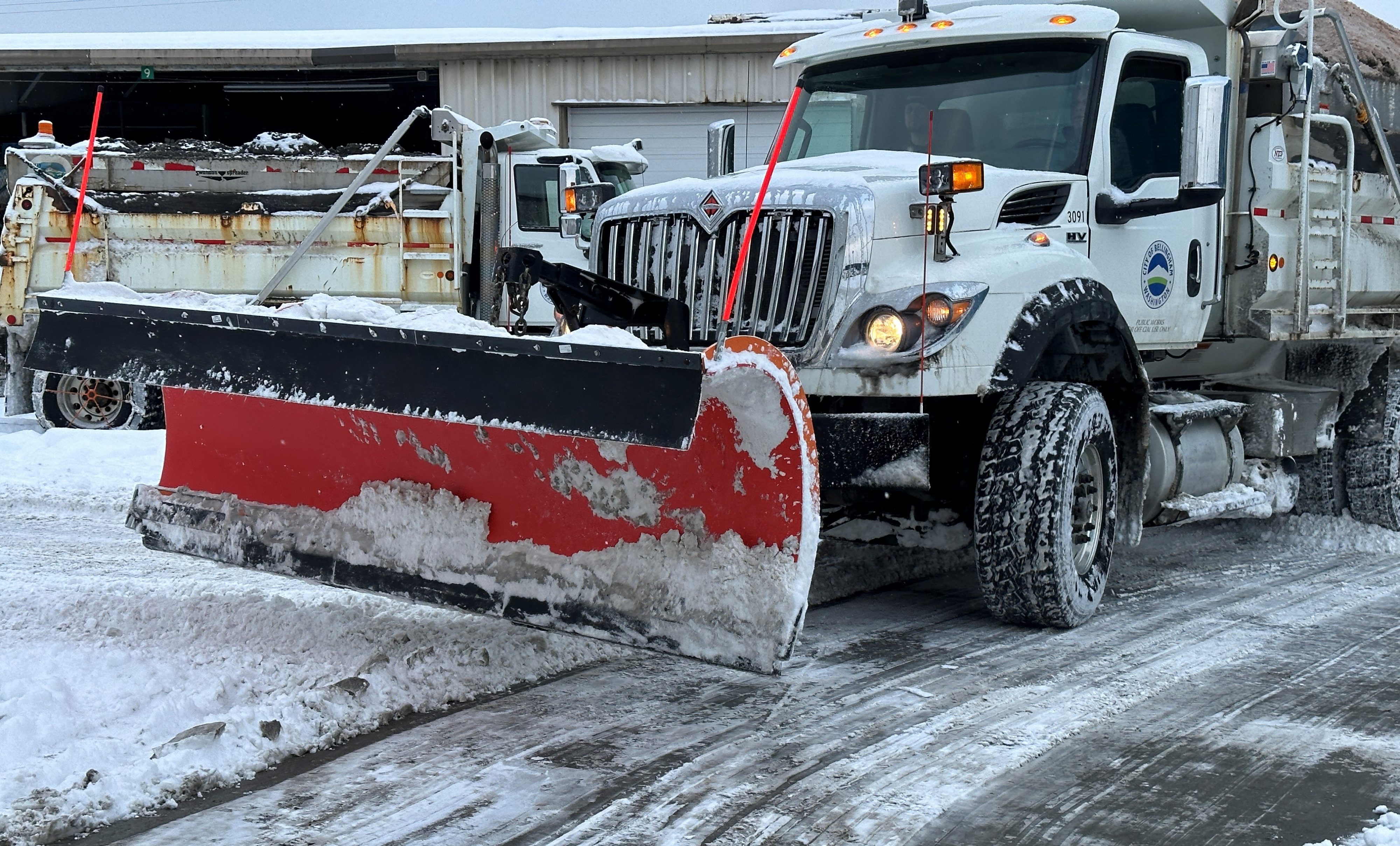 snow covered plow parked in parking lot