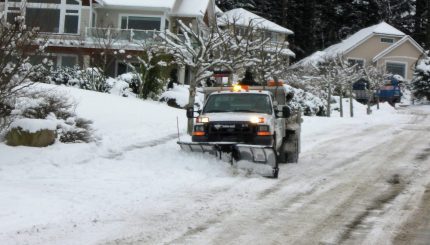 large utility truck using snow plow to clear residential street