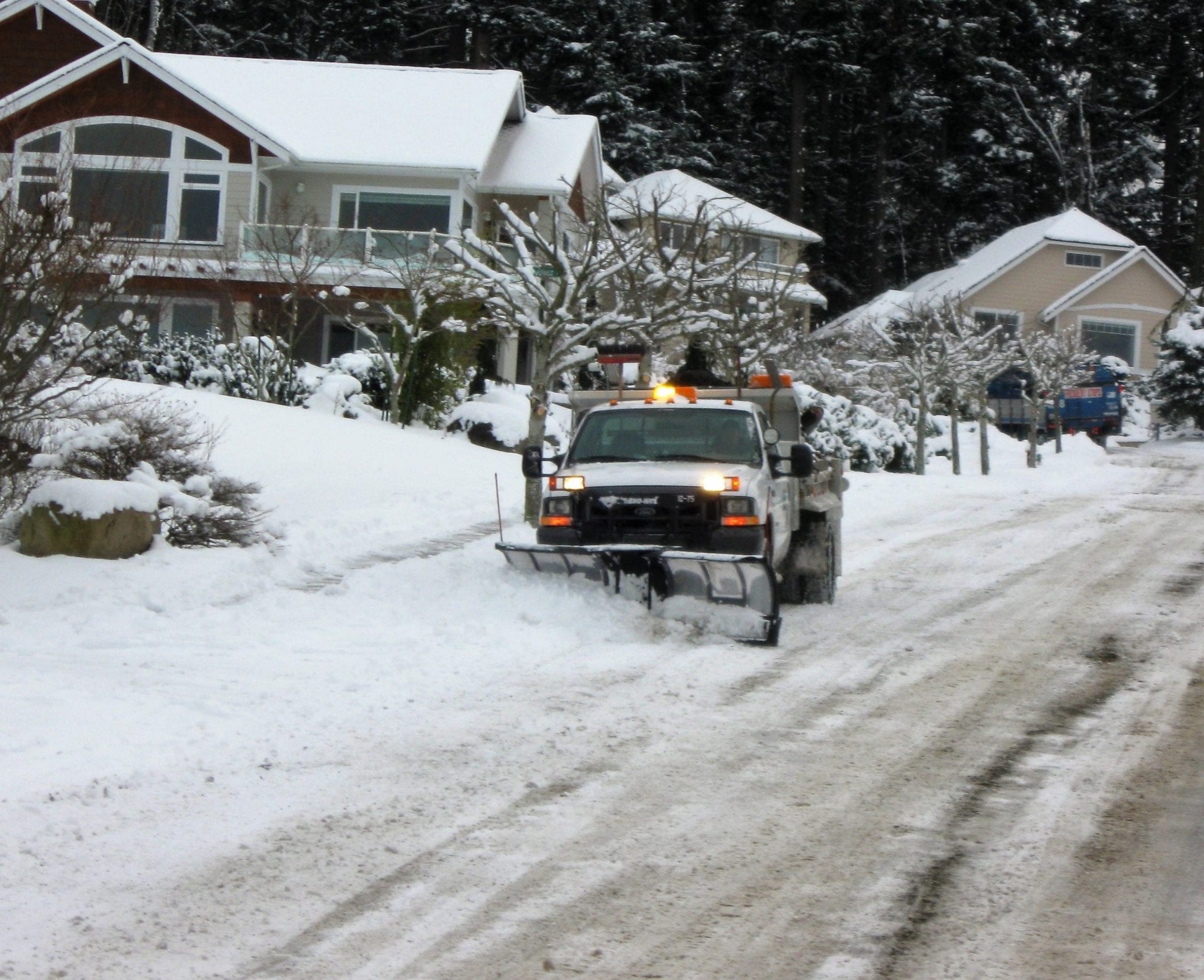 large utility truck using snow plow to clear residential street