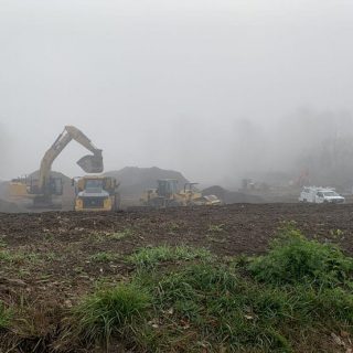 Foggy morning with construction equipment moving dirt in open field