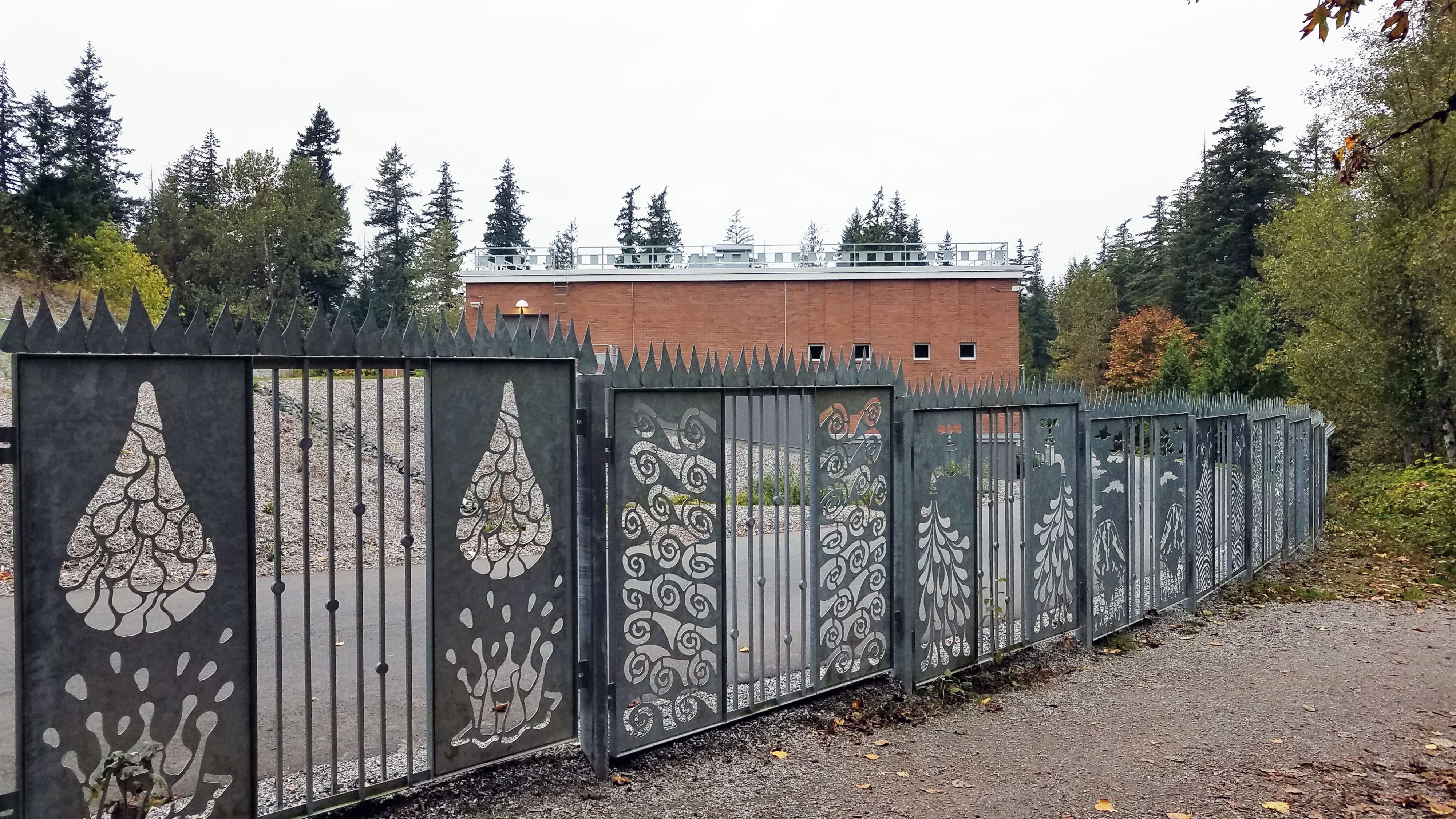 Decorative fence with water treatment plant building in background