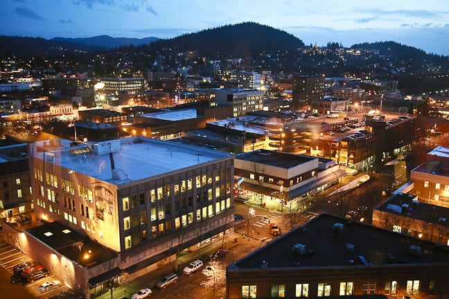 Looking at downtown Bellingham from above. Windows in multi-floor buildings glow yellow at dusk.