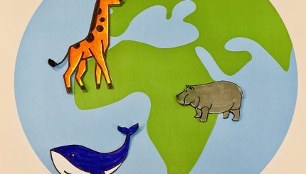 Paper giraffe, hippo, and whale posted on a large paper globe