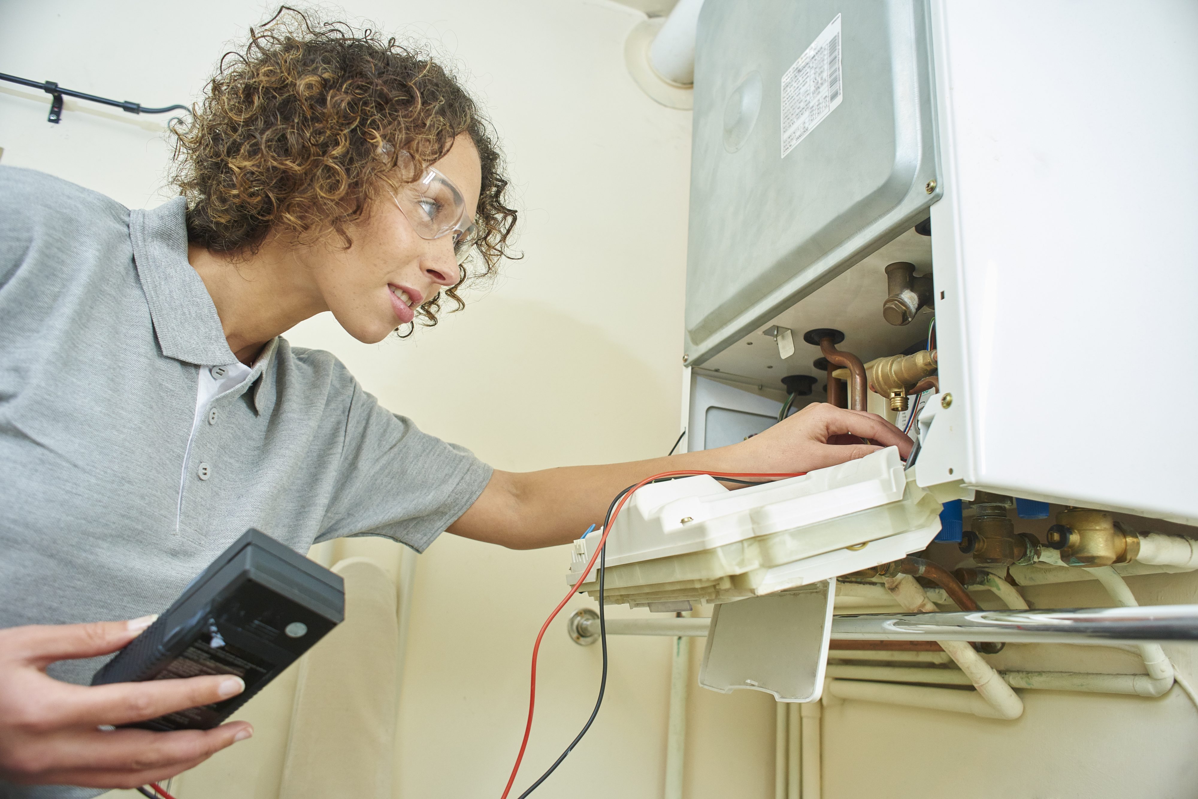A female electrician testing a central heating boiler .