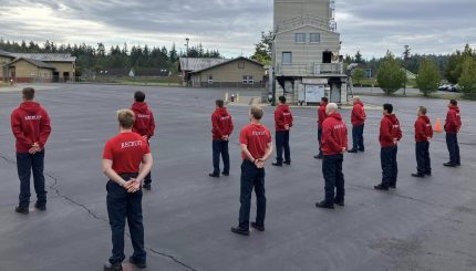 11 people standing in 2 lines in red shirts the say "recruit" on the back