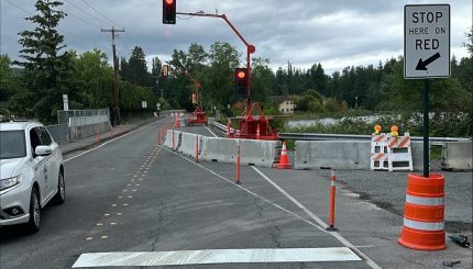 Temporary traffic lights over bridge with line in road and "stop here on red" sign