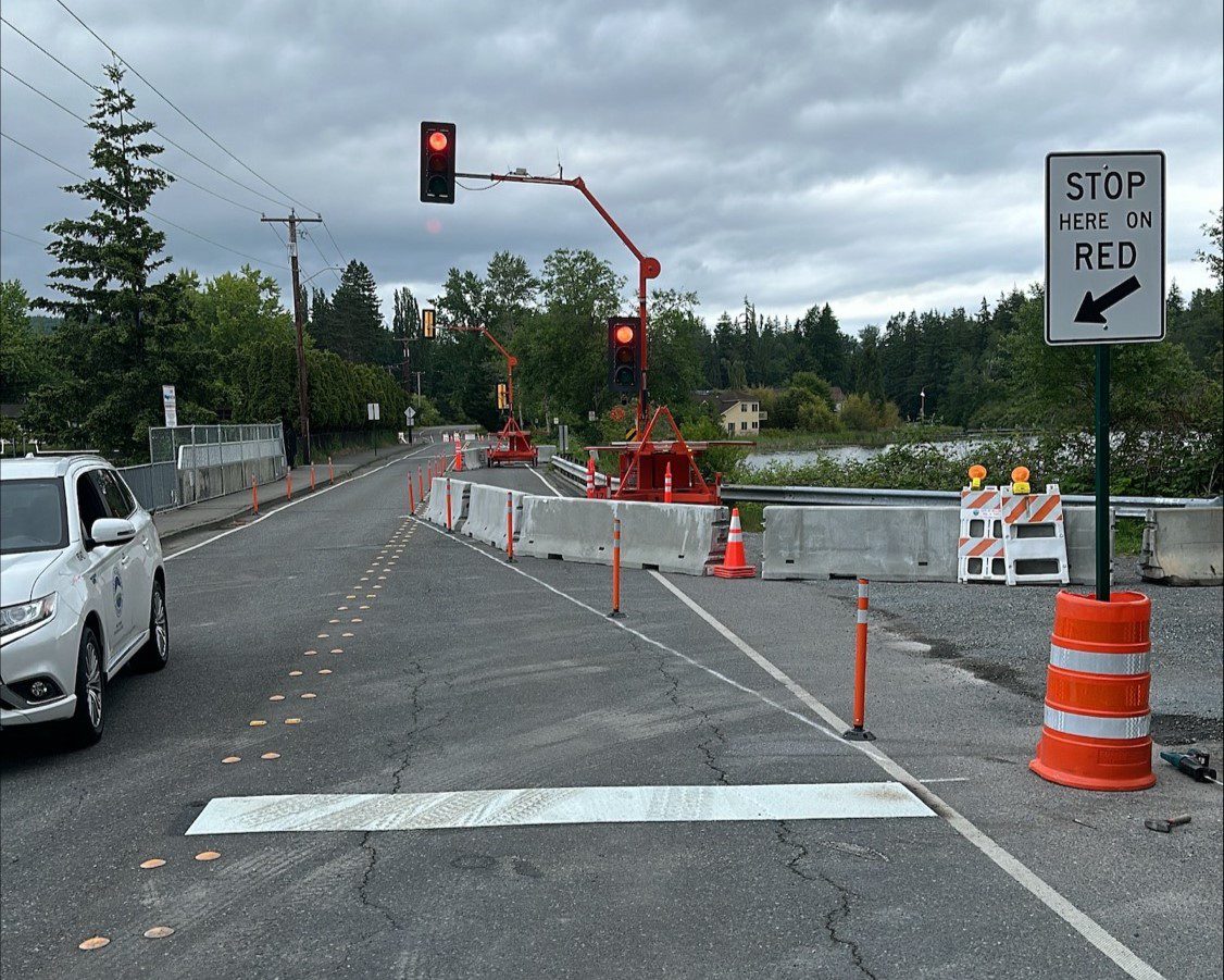 Temporary traffic lights over bridge with line in road and "stop here on red" sign