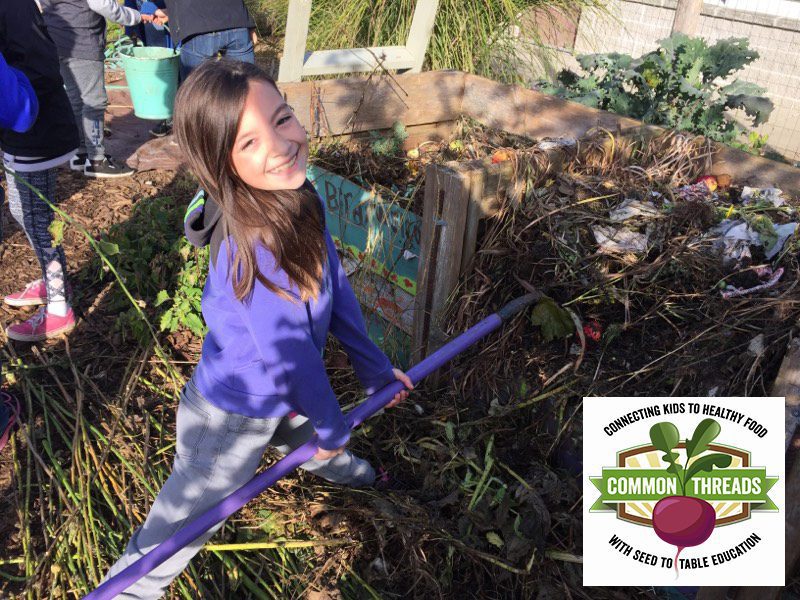 Young girl using rake in compost bin while smiling. Common Threads logo in bottom right.